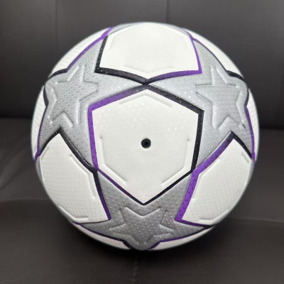 Bola de futebol branca com estrelas cinzentas, detalhes roxos e textura pontilhada.