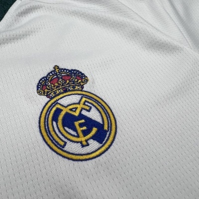 Emblema bordado do Real Madrid numa camisola de malha branca.
