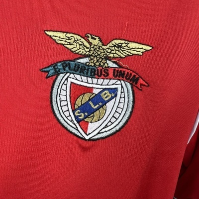 Logótipo bordado colorido em fundo vermelho com uma águia dourada e escudo com texto