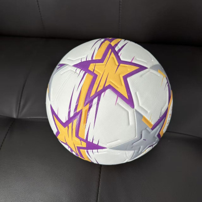 Bola branca com estrelas amarelas e roxas sobre sofá preto