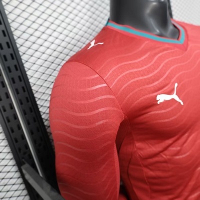 Camiseta desportiva vermelha com logótipo Puma branco e gola detalhe azul e verde em manequim