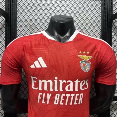Camisola de futebol vermelha com logos e texto branco em manequim preto.