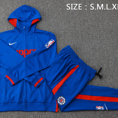 Conjunto desportivo azul com detalhes vermelhos e logos NBA e Nike sobre fundo cinzento.