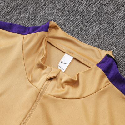 Camisola desportiva dourada com detalhes roxos e logo Nike