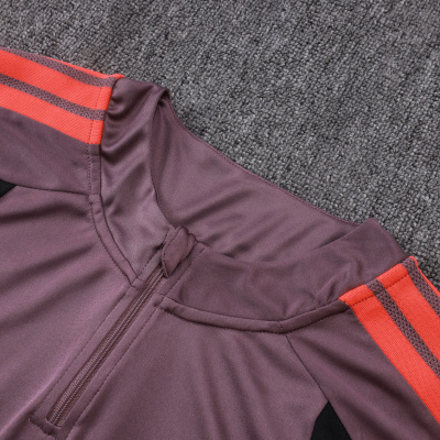 Parte superior de roupa desportiva roxa com riscas laranja nas mangas e zíper curto