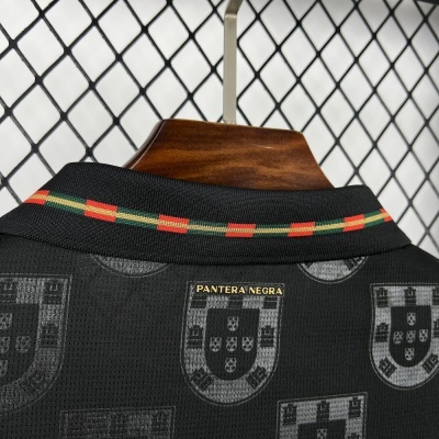 Polo preto com padrão do escudo de Portugal e gola com riscas vermelhas e verdes.