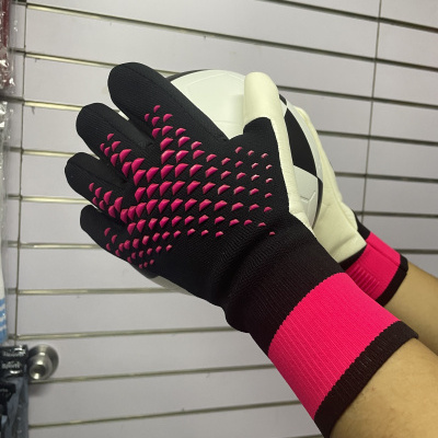 Luvas desportivas em preto e rosa segurando uma bola preta e branca