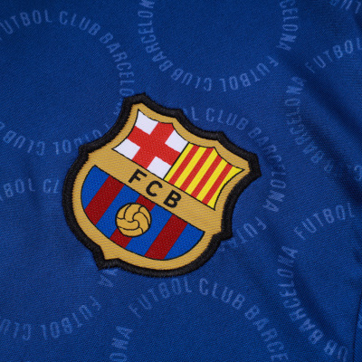 Tecido azul com escudo do FC Barcelona bordado e texto circular repetido.