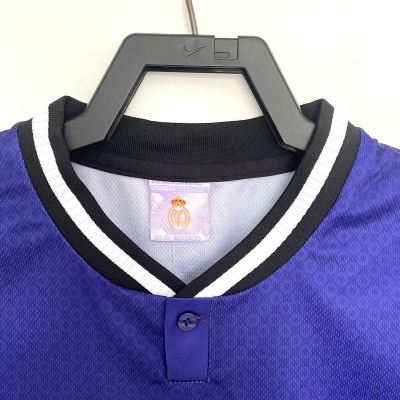 Camisola desportiva azul com gola preta e branca em cabide preto com logo Nike e etiqueta interna Real Madrid