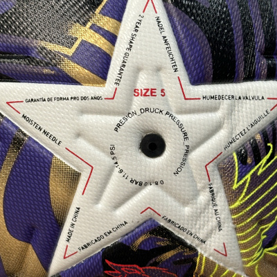 Bola de futebol colorida com válvula branca em estrela e textos em várias línguas