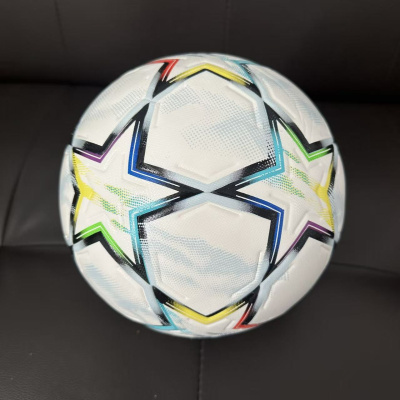 Bola de futebol branca com estrelas coloridas sobre sofá preto