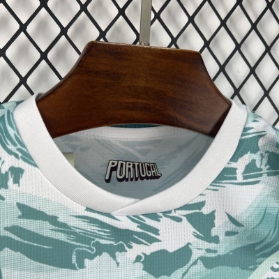 Camisola branca com padrão azul esverdeado e etiqueta PORTUGAL pendurada num cabide de madeira