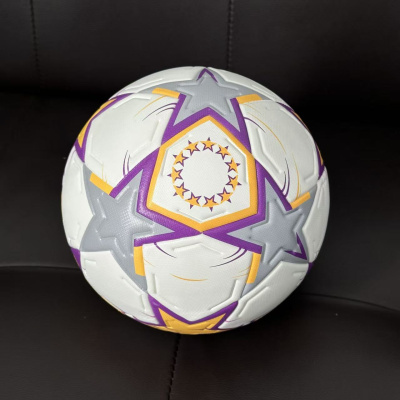 Bola de futebol branca com estrelas coloridas sobre sofá escuro