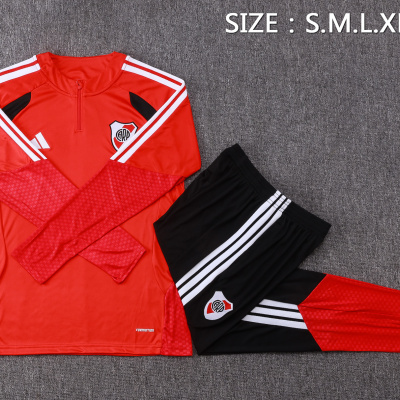 Conjunto de roupa desportiva vermelha e preta sobre tapete cinzento com texto de tamanhos
