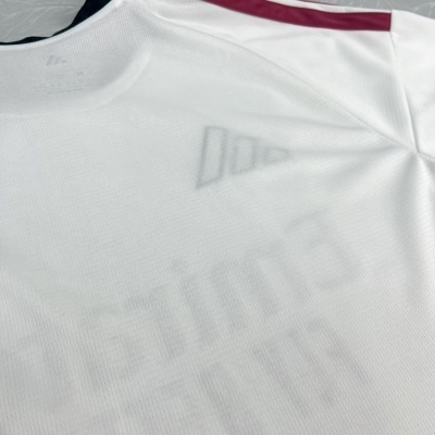 T-shirt desportiva branca com painel vermelho no ombro e texto impresso.