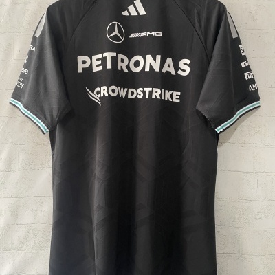 T-shirt preta com logos brancos PETRONAS, CROWDSTRIKE, AMG, Mercedes e adidas pendurada