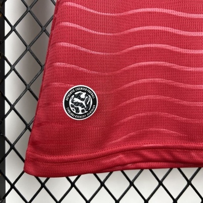 Tecido vermelho ondulado com etiqueta Authentic Licensed Football pendurado numa rede preta.
