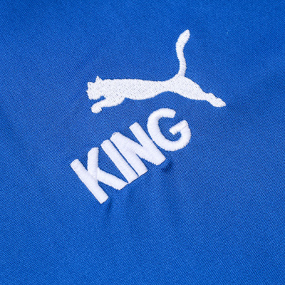 Bordado branco com animal a saltar e palavra KING em tecido azul
