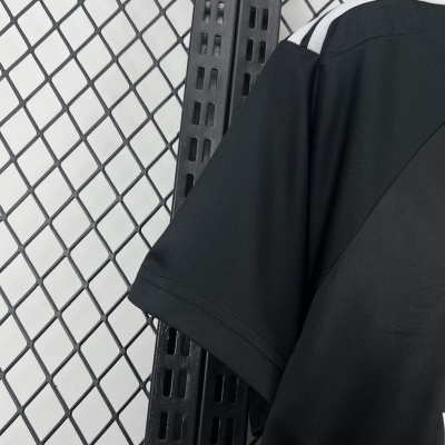 T-shirt preta com costura dupla na manga, listra branca no ombro, fundo de rede metálica preta