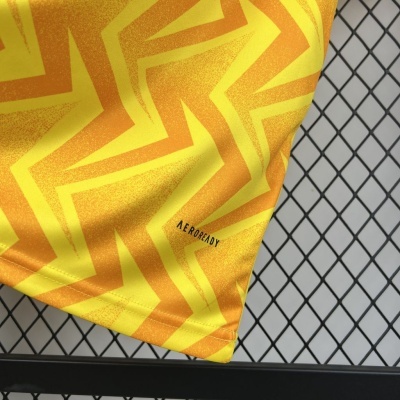 Tecido amarelo e laranja com padrão zig zag e texto AEROREADY em superfície de grelha