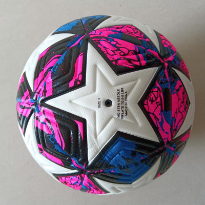 Bola de futebol branca com detalhes coloridos em rosa, azul e preto e texto impresso