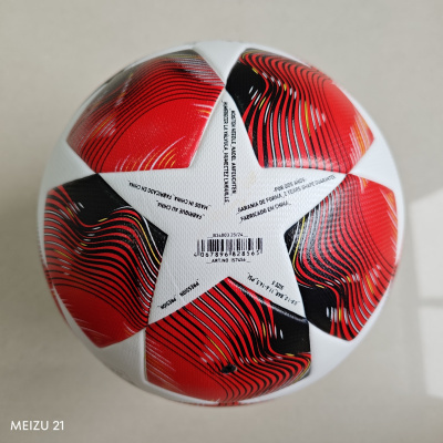 Bola de futebol branca com padrões vermelhos e pretos e texto impresso