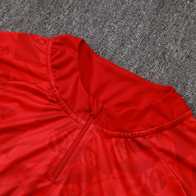 Camisa desportiva vermelha com padrão repetido e fecho à frente.