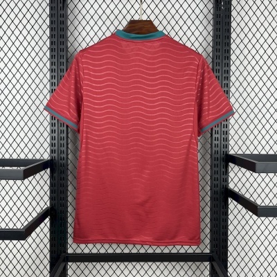 T-shirt vermelha com linhas onduladas e detalhes verdes na gola e mangas pendurada numa cabide