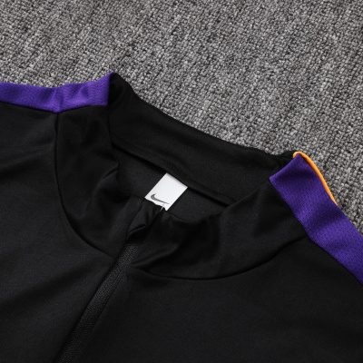 Parte de roupa desportiva preta com risca roxa e detalhe laranja e etiqueta Nike