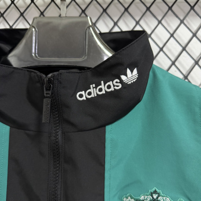 Casaco Adidas com gola preta e logótipo bordado branco, corpo verde água e bordado floral, pendurado numa cabide de metal