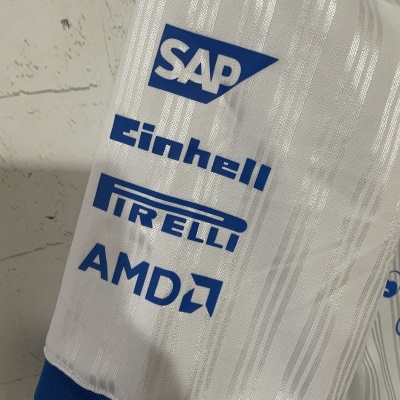 Tecido branco com logótipos azuis SAP, Einhell, Pirelli e AMD