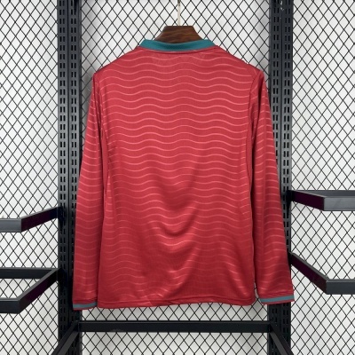 T-shirt de manga comprida vermelha com padrão ondulado e gola verde e coral pendurada num suporte metálico