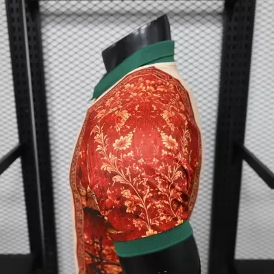 Camiseta vermelha com padrão floral amarelo, gola e punhos verdes, em manequim preto