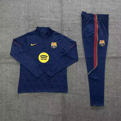 Conjunto roupa desportiva azul escuro com emblema do FCB e logótipos Nike e Spotify.