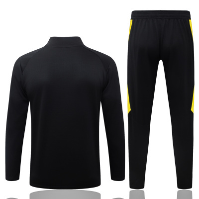 Conjunto desportivo preto com riscas amarelas, camisola manga comprida e calças justas.