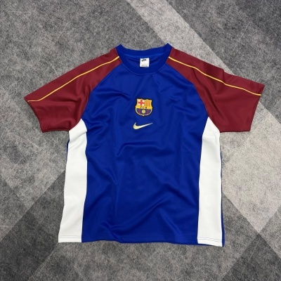 Camisola desportiva azul com mangas castanho-avermelhadas e logótipos FC BARCELONA e NIKE.