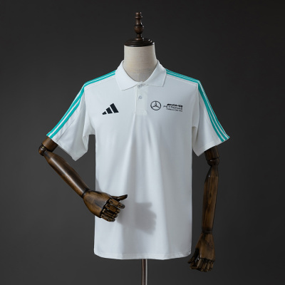 Polo branco com riscas azul turquesa nas mangas e logótipos AMG, Mercedes, PETRONAS e Adidas, colocado em manequim de madeira.