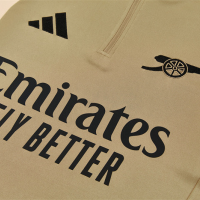 T-shirt desportiva bege com logos Arsenal FC, Adidas e texto Emirates FLY BETTER