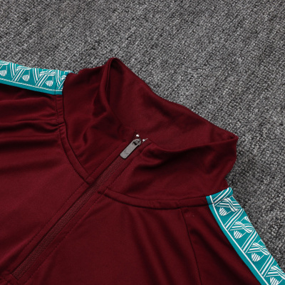 Camisola desportiva bordô com gola alta, fecho e lista verde decorativa nas mangas