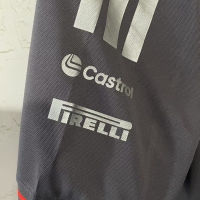 Manga de peça de vestuário cinzenta com logos CASTROL e PIRELLI em branco e borda vermelha