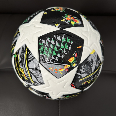 Bola de futebol branca com padrões pretos e florais coloridos em fundo preto.