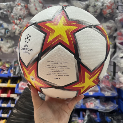 Bola de futebol branca decorada com estrelas amarelas e vermelhas e texto UEFA Champions League