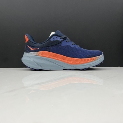 Ténis desportivo azul com detalhes laranja sobre superfície branca e fundo preto