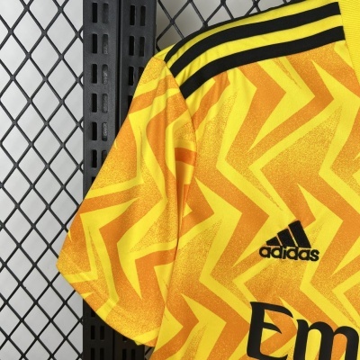 Camisola desportiva Adidas amarela com padrão laranja e riscas pretas no ombro.