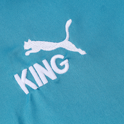 Bordado branco de um felino a saltar e a palavra KING em tecido azul