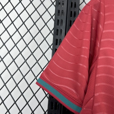Manga de t-shirt vermelha com riscas e ribete azul e vermelho pendurada numa estrutura metálica preta