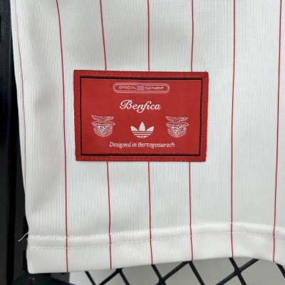 Etiqueta vermelha com texto e logótipos numa peça de roupa branca às riscas vermelhas.