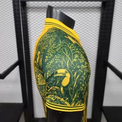 T-shirt desportiva verde e amarela com padrão de tucanos e plantas num manequim preto