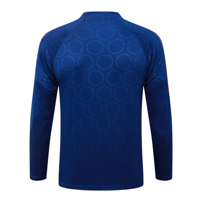 Camisola desportiva azul escura de manga comprida com padrão circular e texto FUTBOL CLUB BARCELONA.