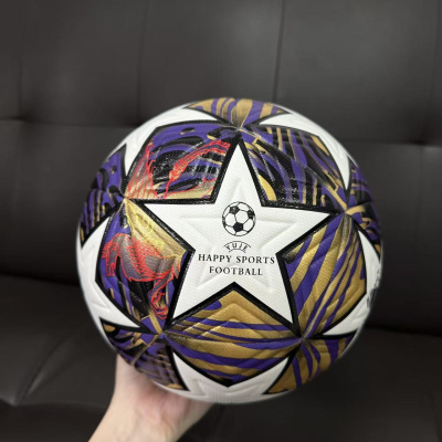 Bola de futebol branca com estrelas e padrões coloridos sendo segurada por uma mão